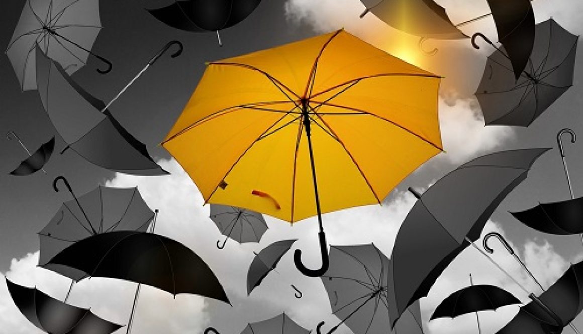 Yellow umbrella in a sea of grey umbrellas