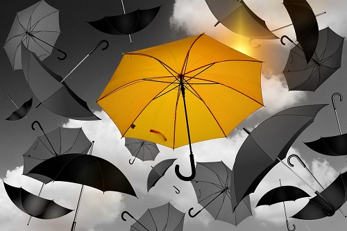 Yellow umbrella in a sea of grey umbrellas
