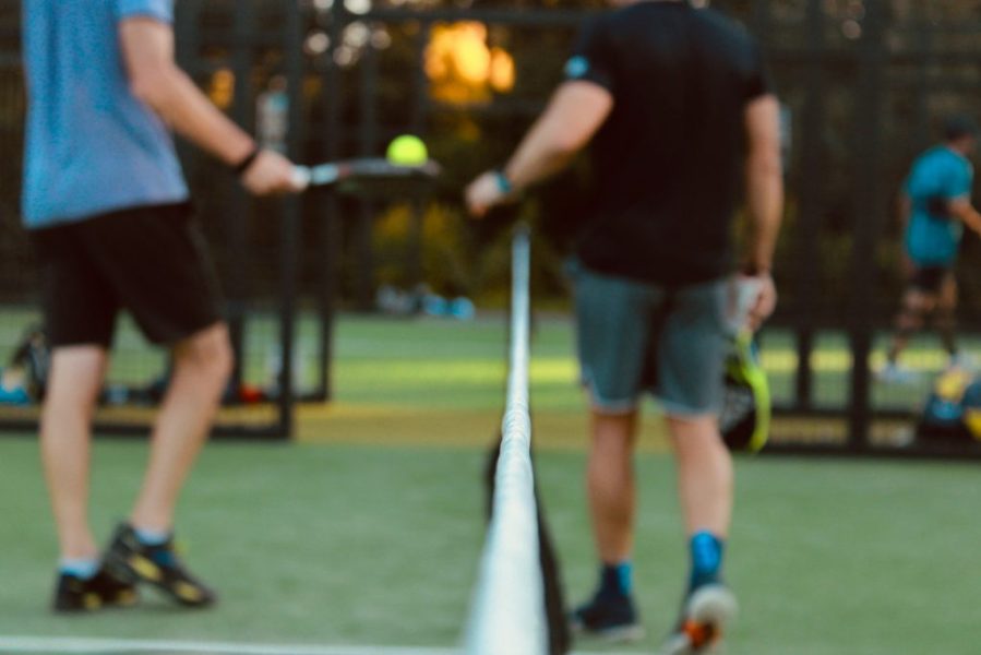 two padel players on a court with net between them